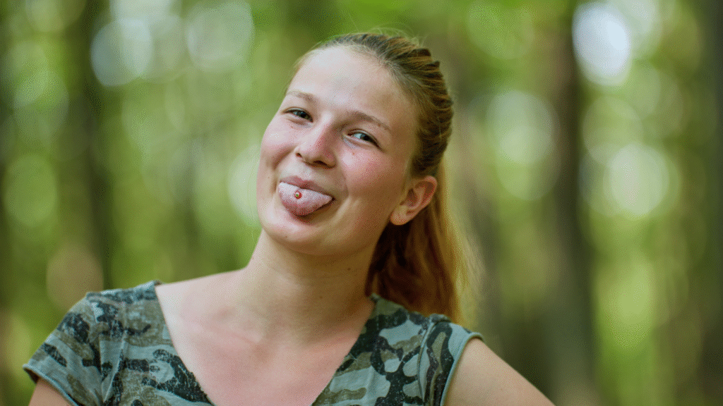 Los impactantes riesgos para la salud de las perforaciones bucales 1 - Odontología profesional Young woman showing a tongue piercing; a common oral body modification with dental risks.