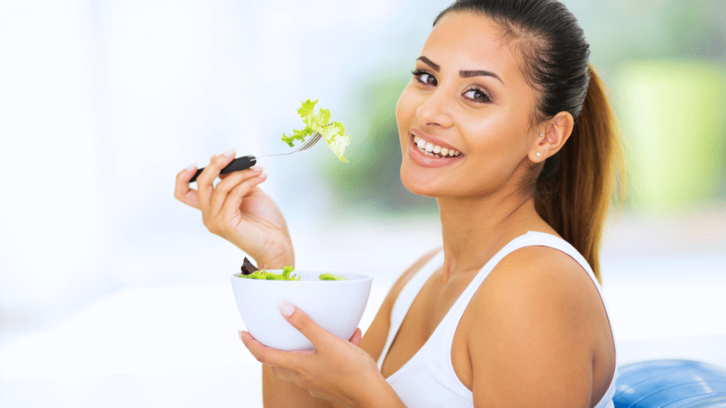 Smiling woman enjoying fresh fruits and vegetables, promoting good dental health and nutrition.