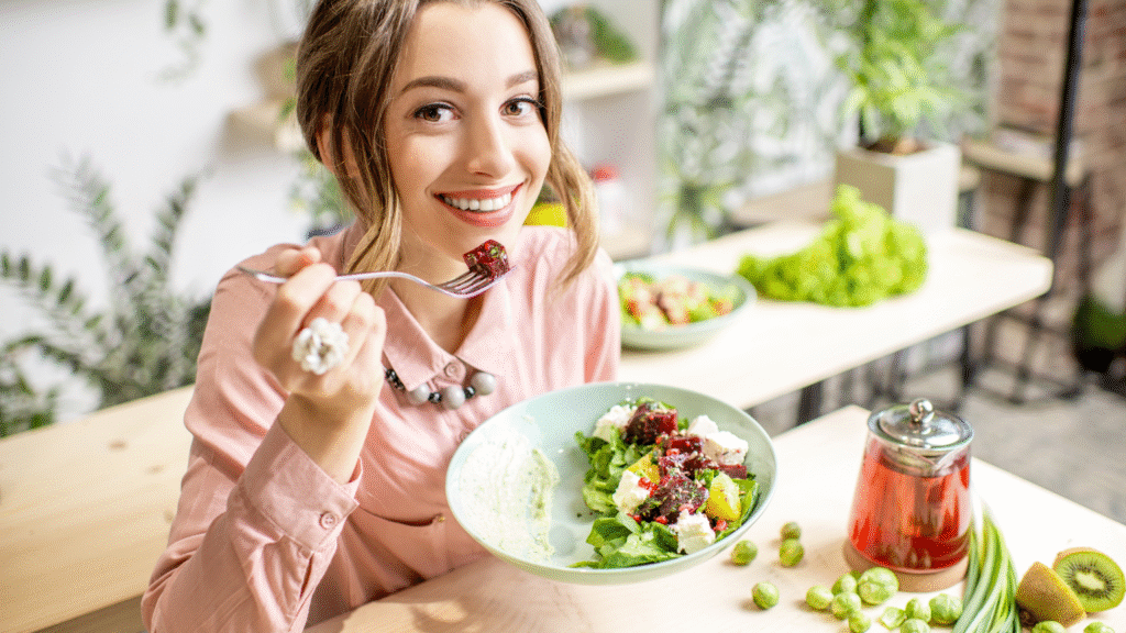 Smiling woman enjoying fresh fruits and vegetables, promoting good dental health and nutrition.
