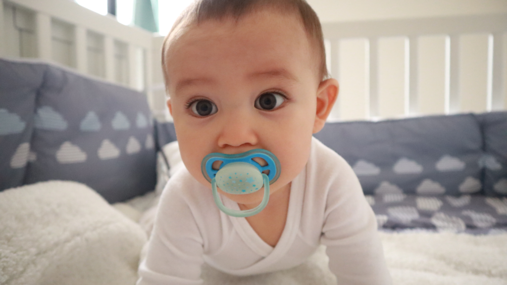 Close-up of a smiling infant happily using a pacifier, emphasizing the need for early orthodontic guidance on oral habits at Professional Dental in Utah.