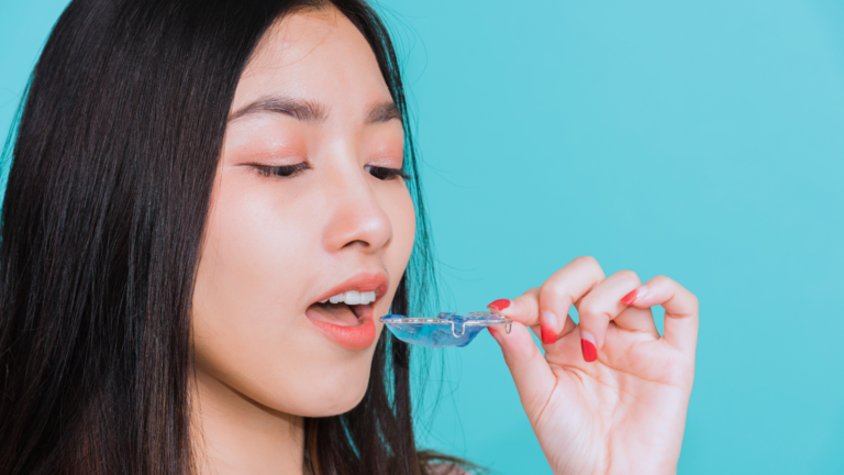 Young woman holding a removable blue orthodontic retainer for a check-up at Professional Dental in Utah.